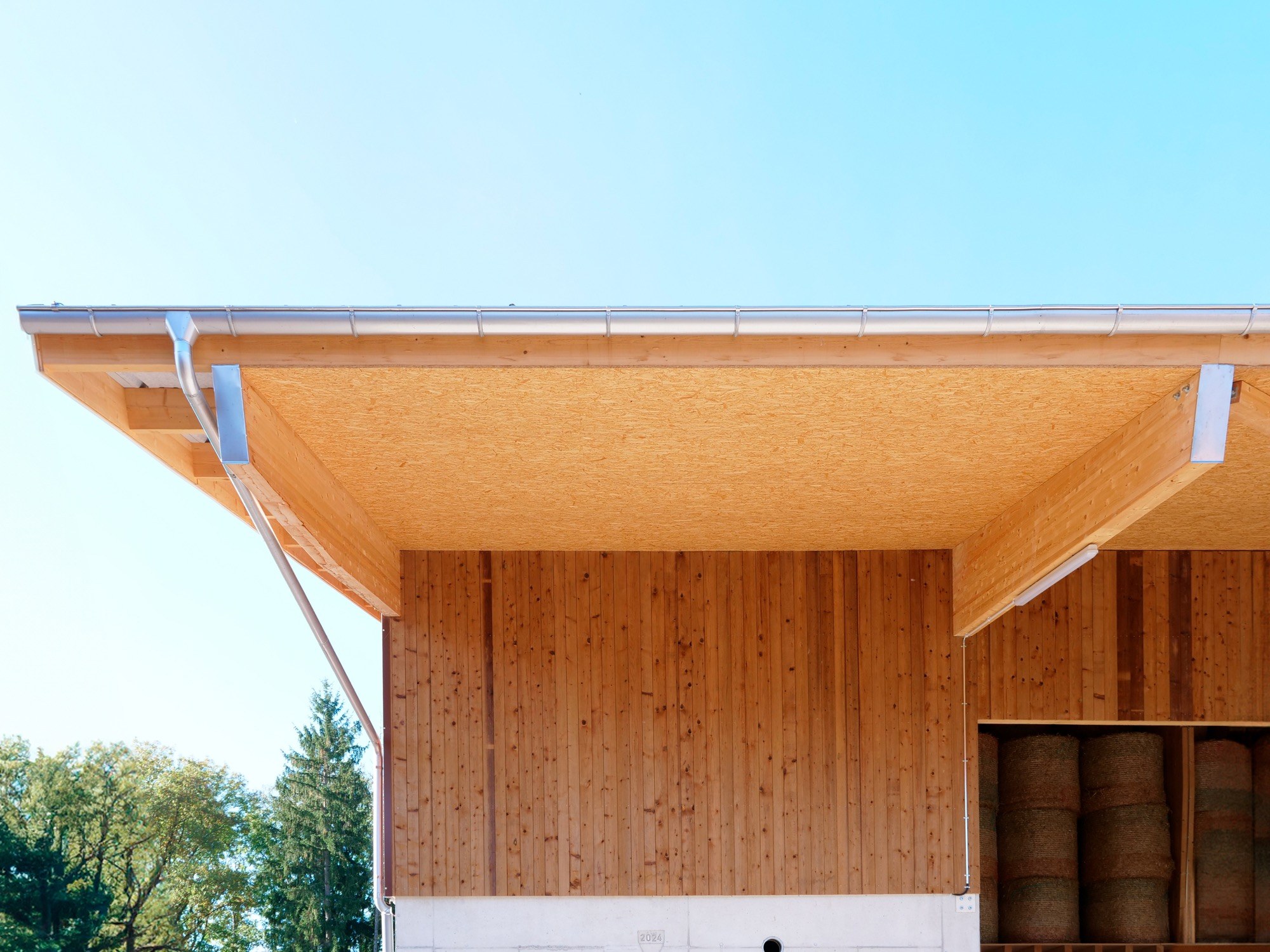 Détail d’une toiture et d’un bardage en bois à Carrouge