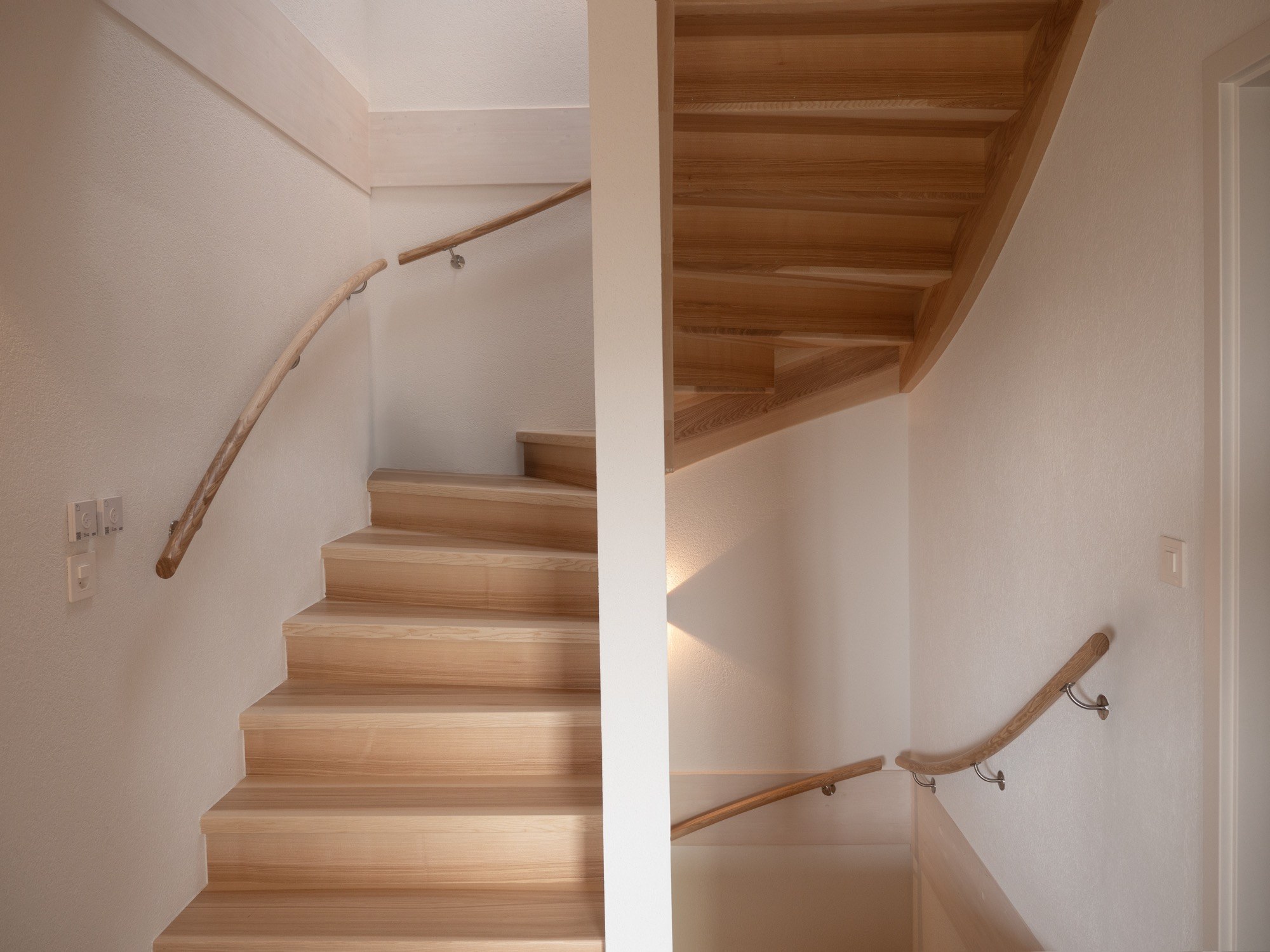 Escalier en bois clair et courbe du mur intérieur